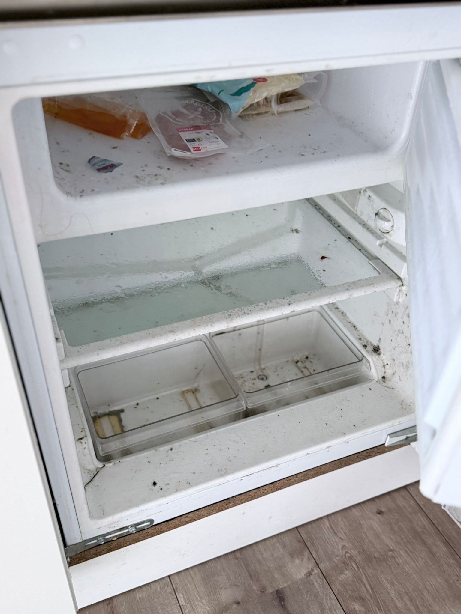 Vieze koelkast met resten en aanslag voor reiniging
